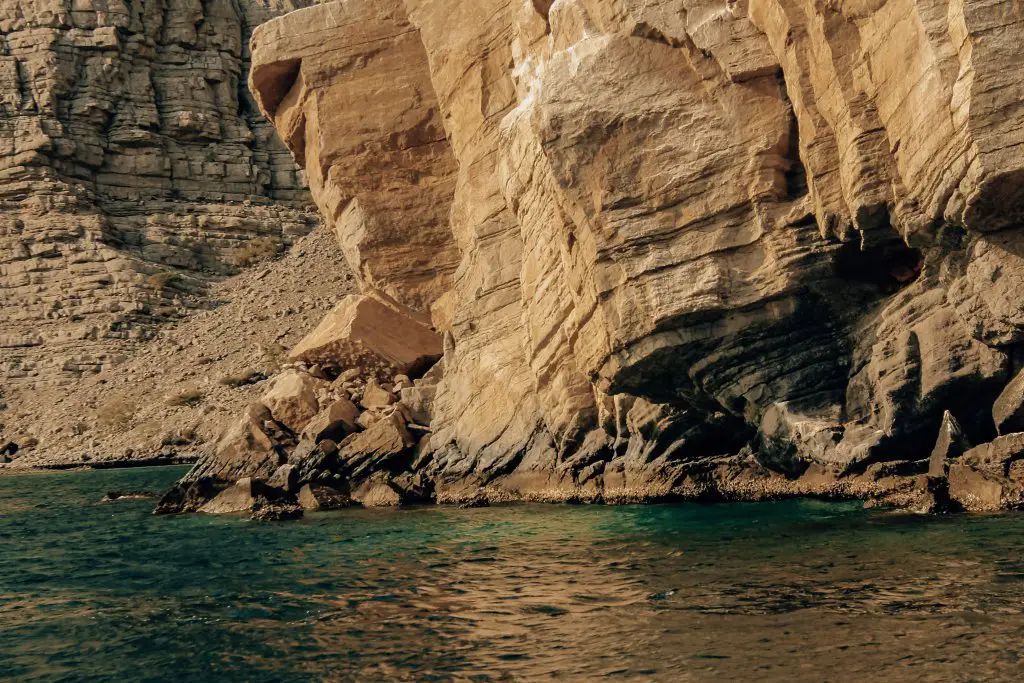 Tall rocky cliffs over the blue Arabian Sea.