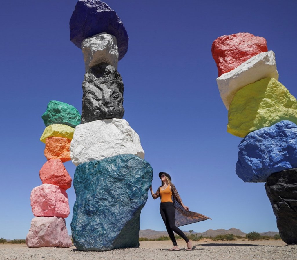 Monica standing next to a rainbow rock in the desert.