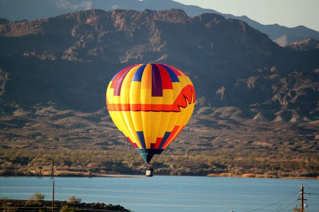 A yellow hot air balloon floating over Lake Havasu, a must see stop on any California to Arizona Road Trip.