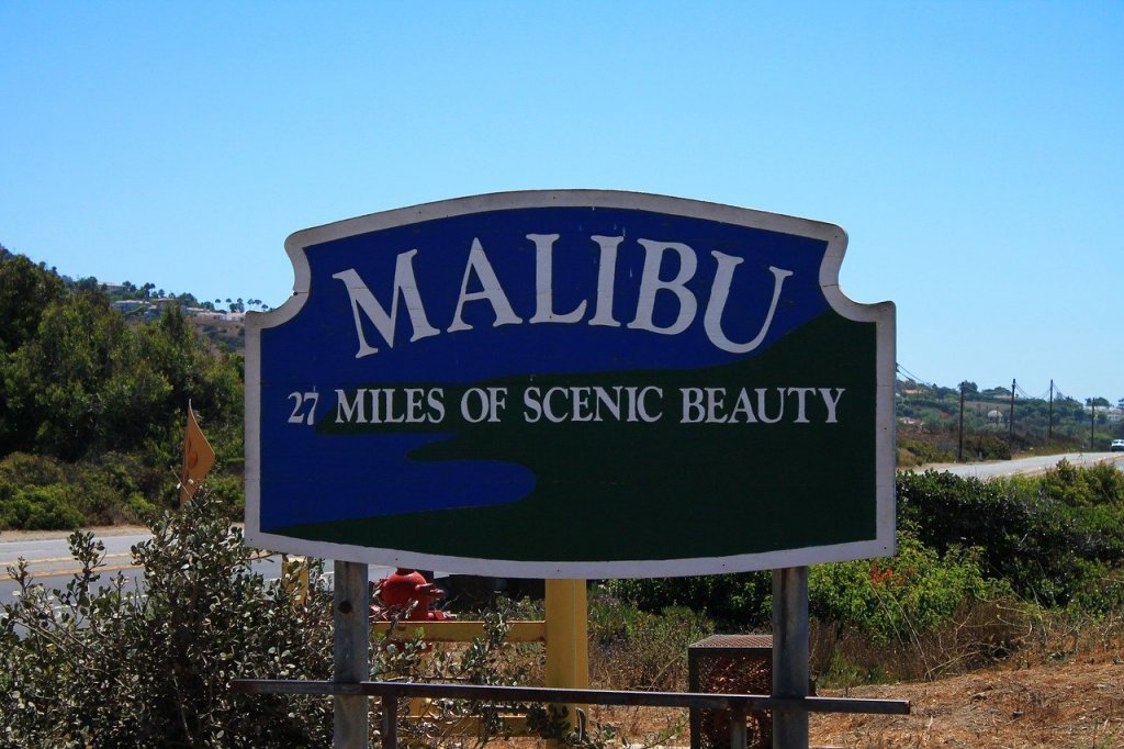 A signpost seen as you drive through Malibu in front of local plant life.