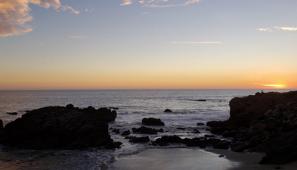 Sunset glowing orange and pink over the ocean at the end of a day trip to Malibu.