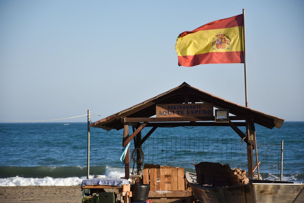 Spanish flag blowing in the wind on the beach.