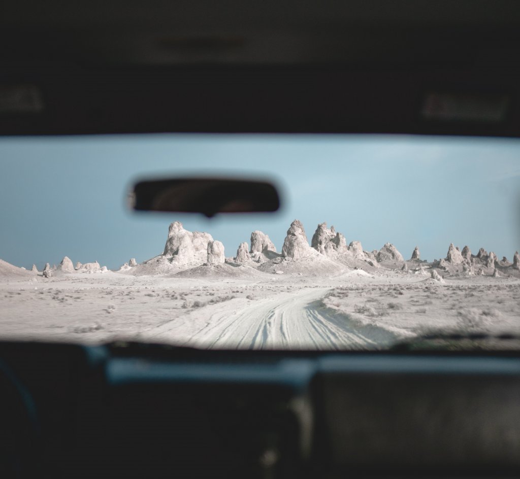 The Trona Pinnacles standing tall in the distance, looking through a car windshield.