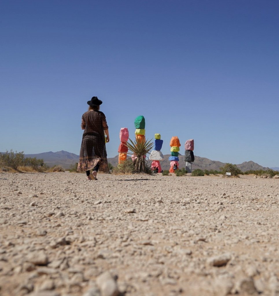 Monica visiting the 7 magic mountains art installation of colorful rocks, a fun thing to do in Mojave Desert.