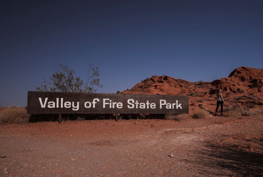 @thisrareearth near the Valley of Fire State Park sign - #1 of The Top 10 Road Trips From Las Vegas 