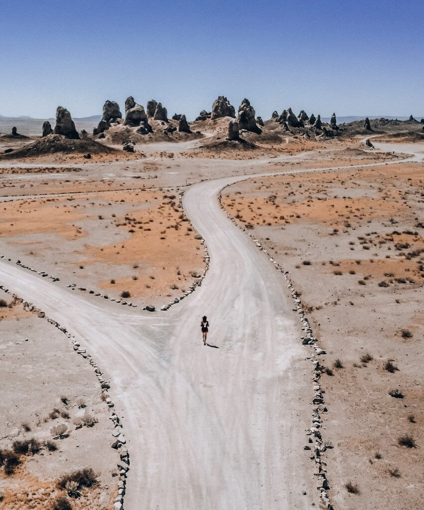 Monica walking to the Trona Pinnacle rock formations, against blue sky.  This is one of the top things to do in Mojave Desert.