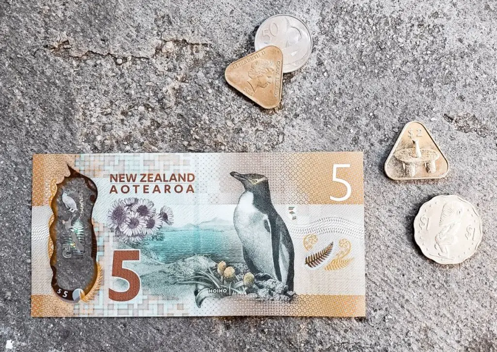 An interesting Cook islands fact: the official currency is the New Zealand dollar.  a $5NZD next to 4 Cook Islands coins.
