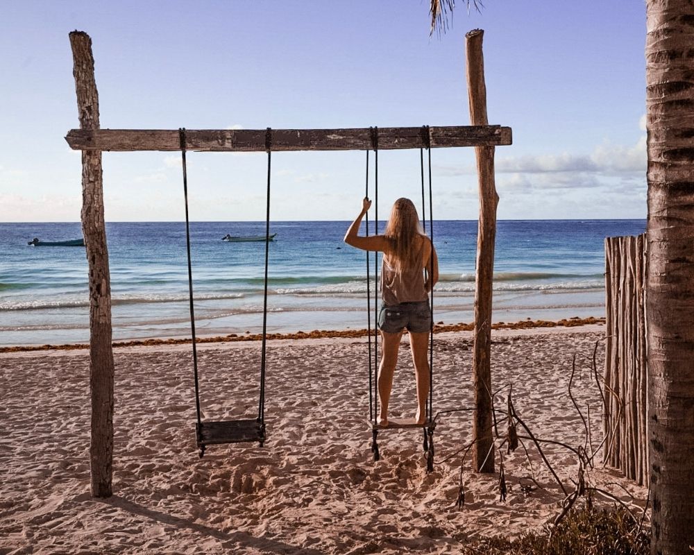 Monica in Tulum on a swing set, looking out into the Caribbean Sea.