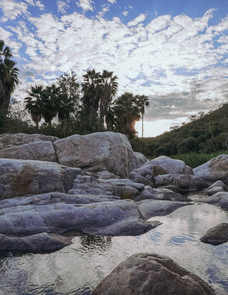 White rocks lining The Santa Rita Hot Springs under cloudy skies.