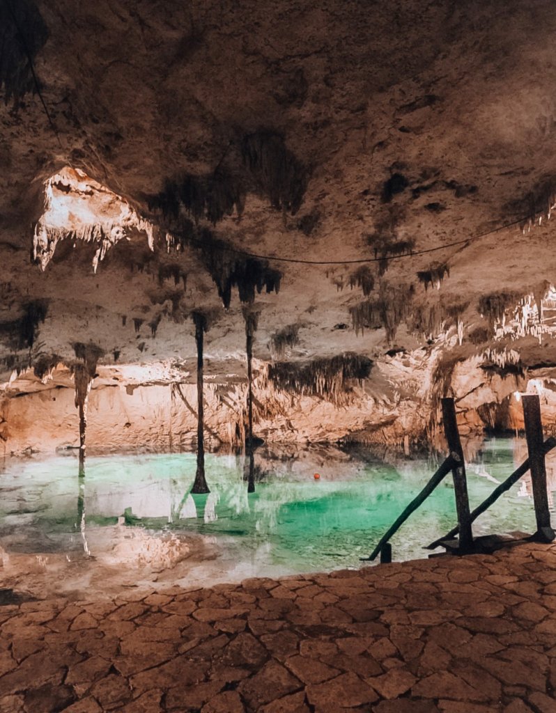 Light shines into the underground cenote, illuminating the blue waters.