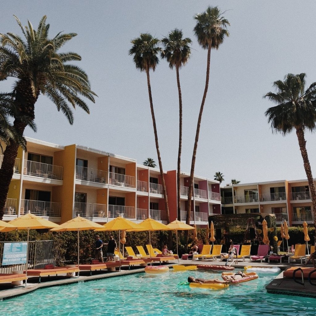 A beautiful blue palm springs pool in front of tall palm trees.