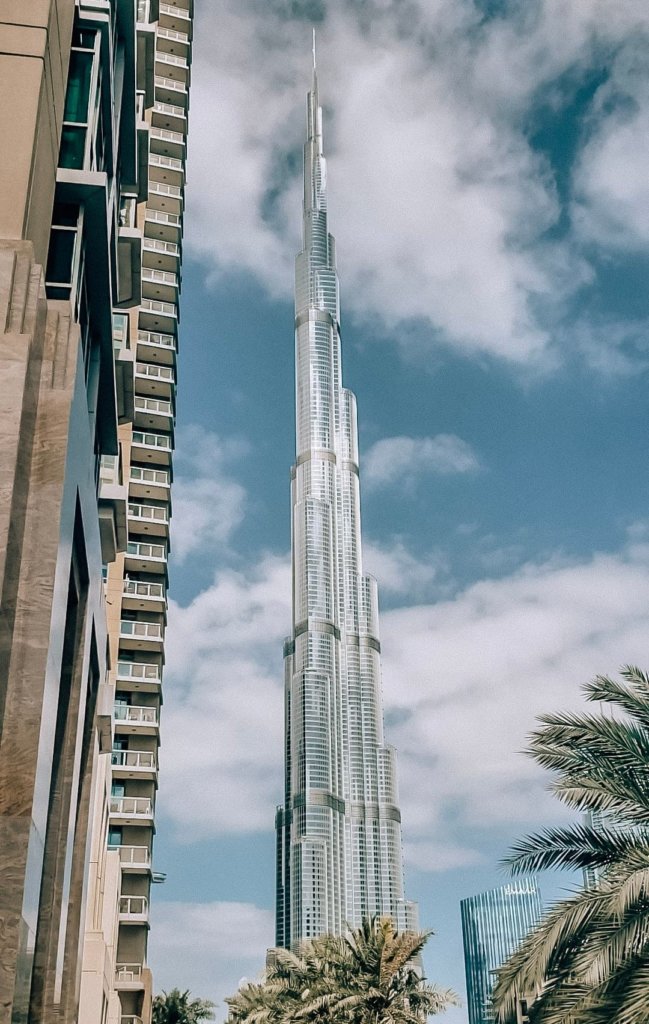 The tall Burj Khalifa in front of a cloudy blue sky.