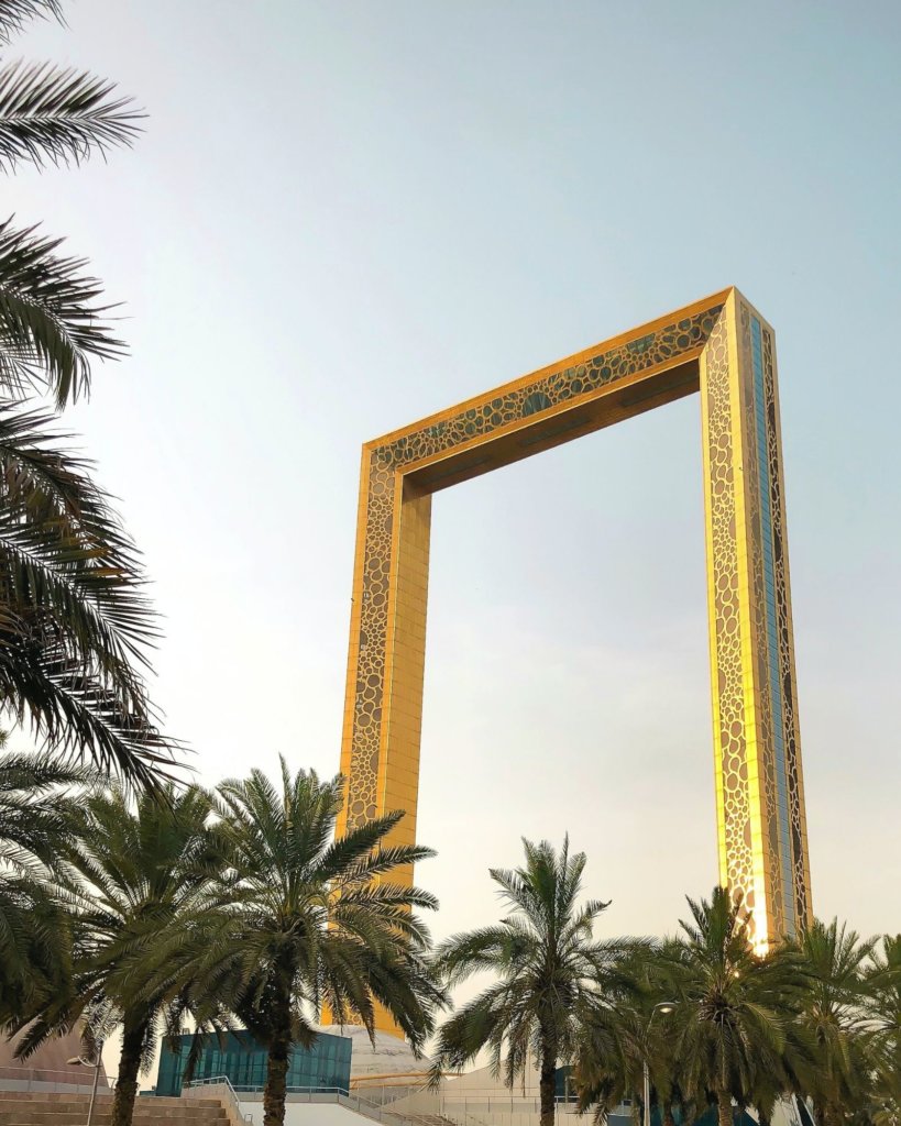 The Golden Frame in Dubai with green palm trees.