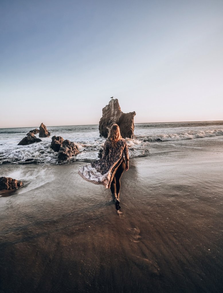 Monica walking the rocky beach in Malibu, one of the best Cheap Weekend Getaways in Southern California.