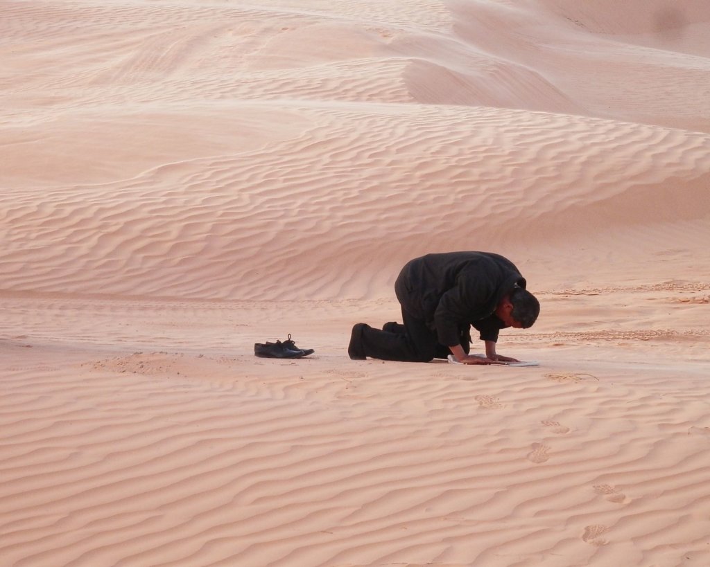 Ten Things Not To Do in Dubai - Don't Disrespect Islam.  Man praying in the desert.