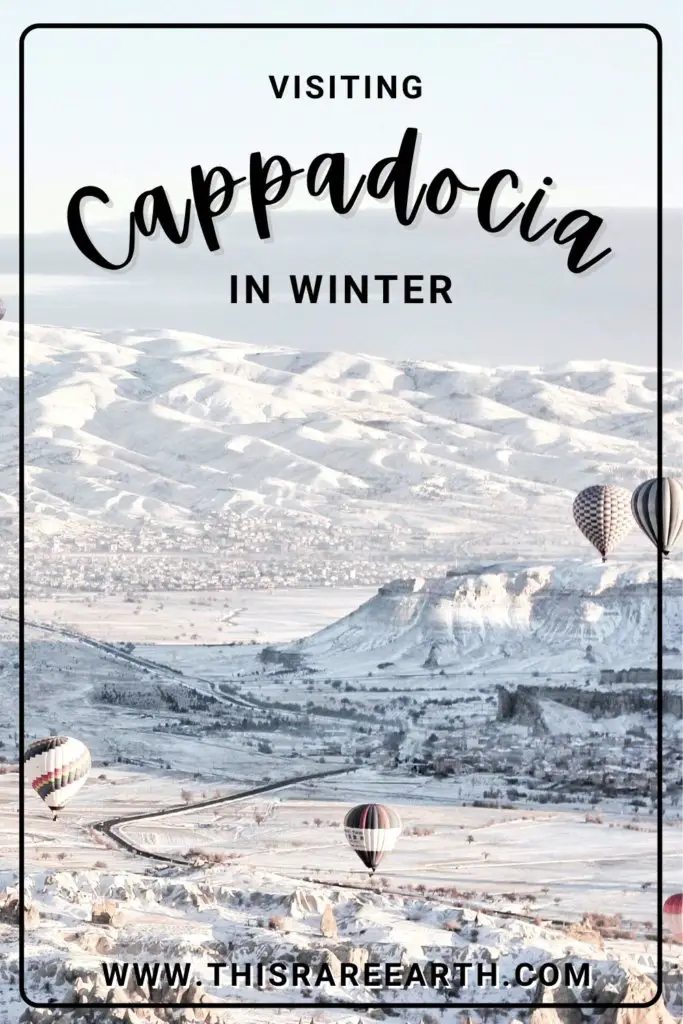 Cappadocia in Winter covered in snow, with hot air balloons rising.