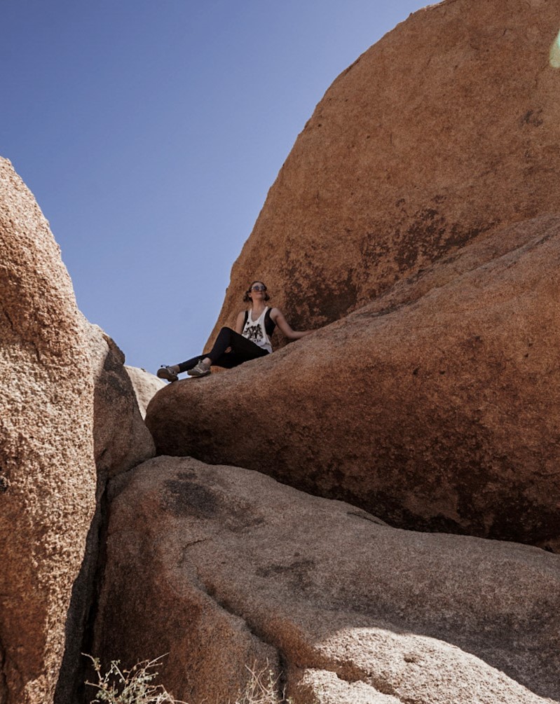 Monica on the large boulders at Joshua Tree National Park -a one day itinerary.