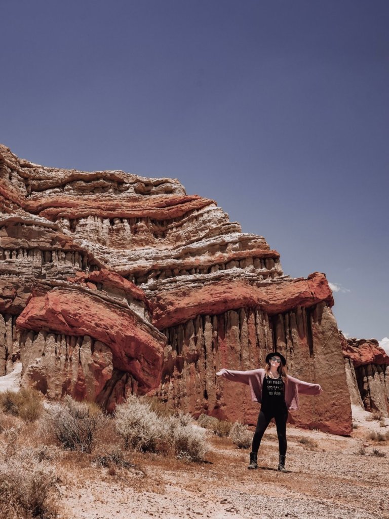 Monica in front of the red desert rocks in Cantil, CA - in the least known desert region park of Southern California.