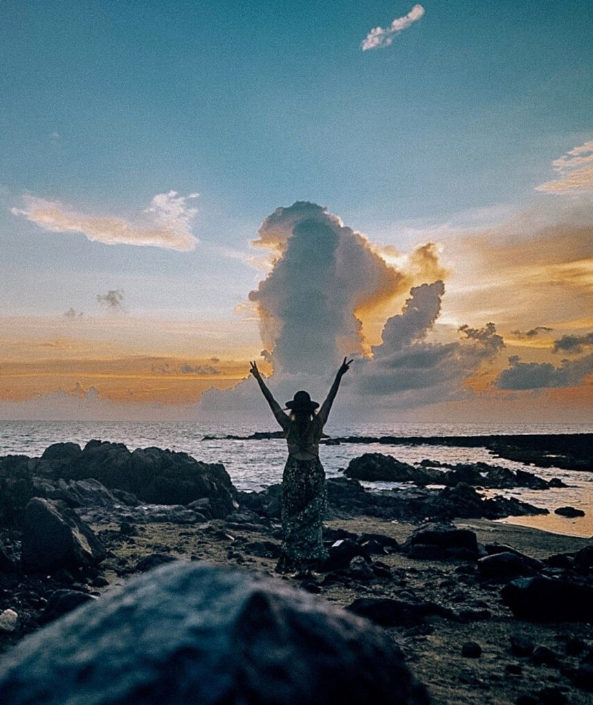 Monica in front of the ocean at sunrise in Aruba, solo female travel in Aruba.