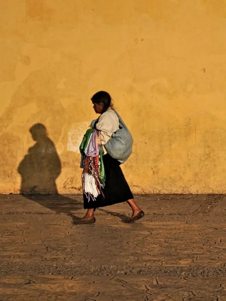 A woman in front of a yellow wall in Mexico.