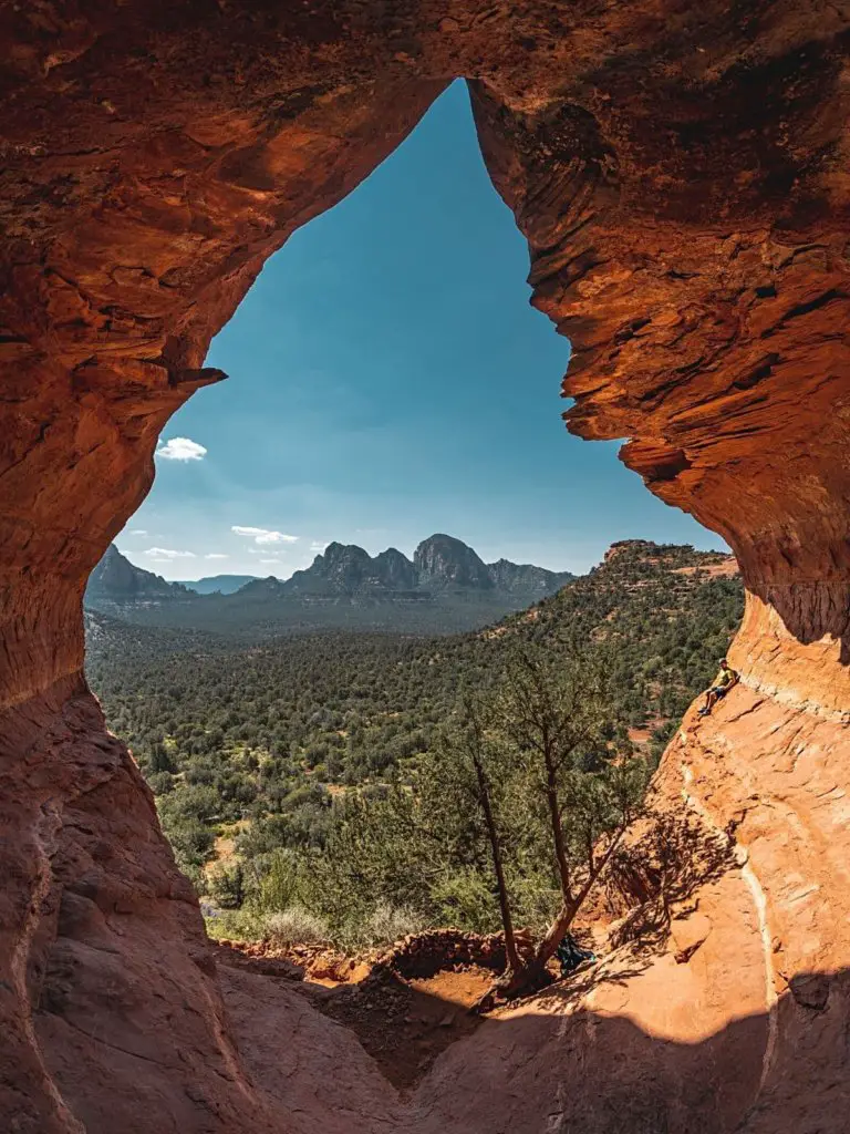The popular Birthing Cave rocks overlooking a green forest below - one of the top things to do in Sedona, Arizona.