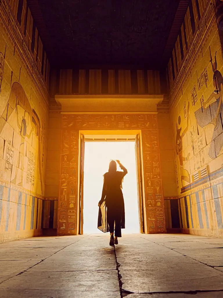 Walking between golden walls into the sun during Solo Female Travel in Egypt: What It's REALLY Like.