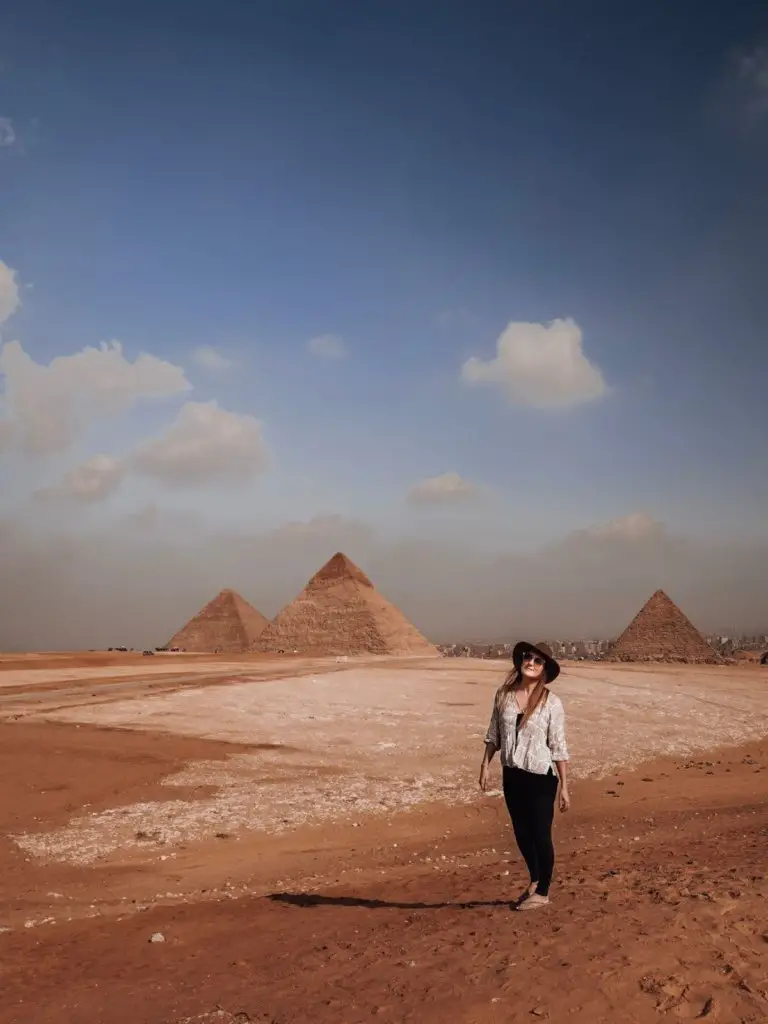 Monica Visiting the Pyramids of Giza in Egypt, standing in the sand.