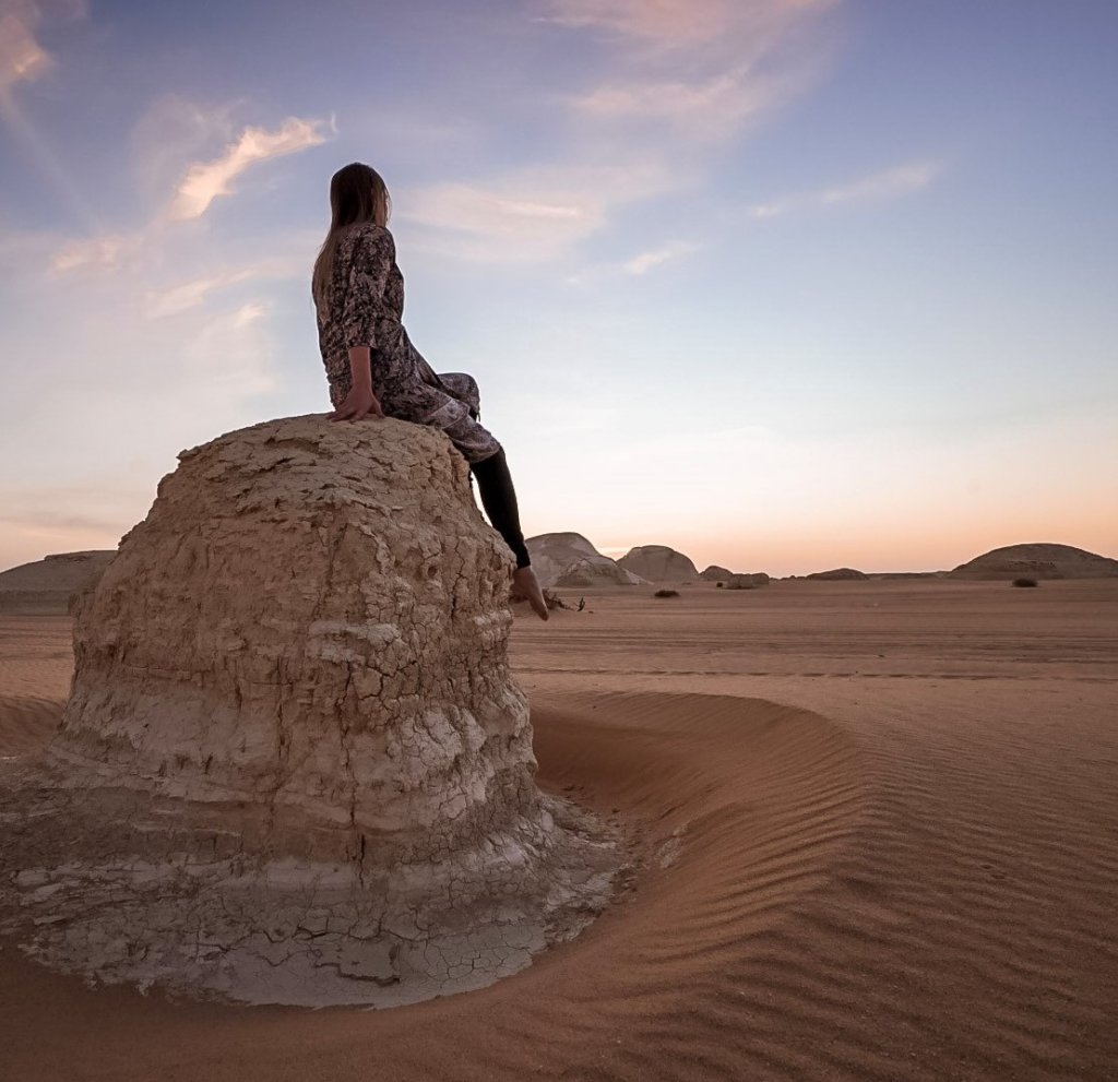 Monica Visiting the White Desert National Park in Egypt, sitting on the rock formations – A Travel Guide to the Black and White Desert.