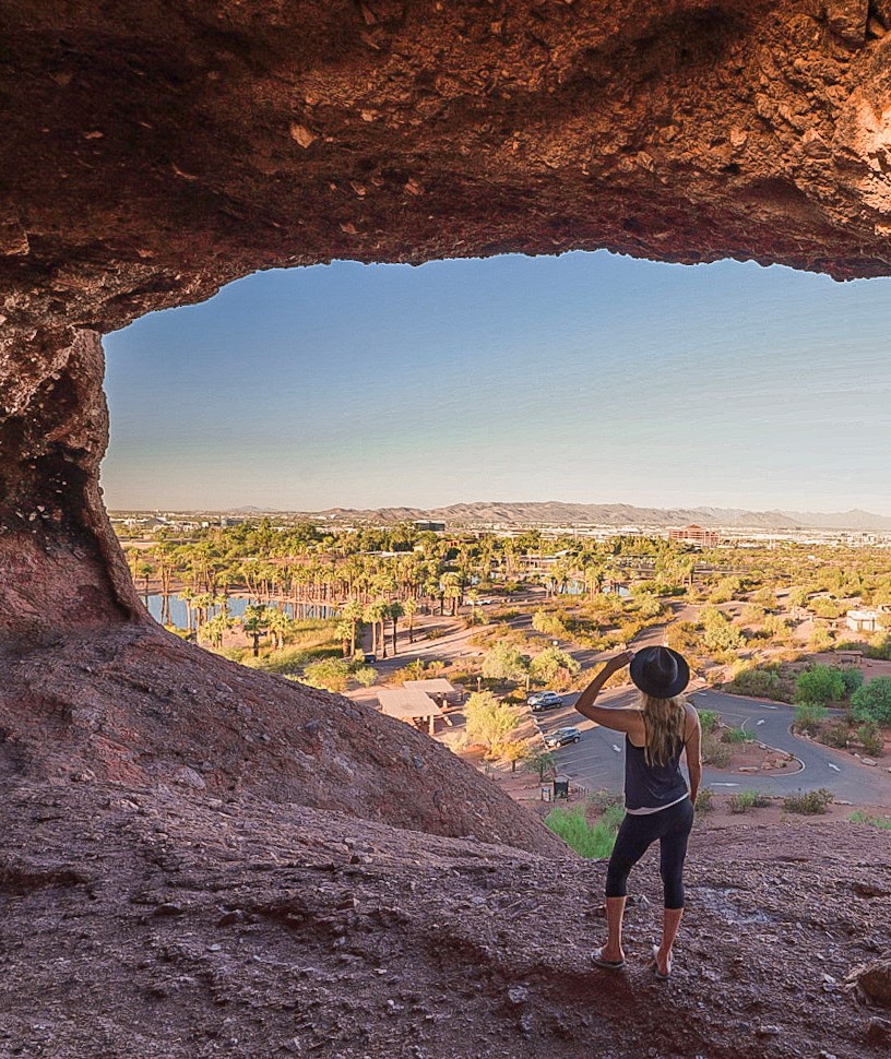 Monica inside the Hole in the Rock Hike in Papago Park, Phoenix, looking out at the green palm trees.