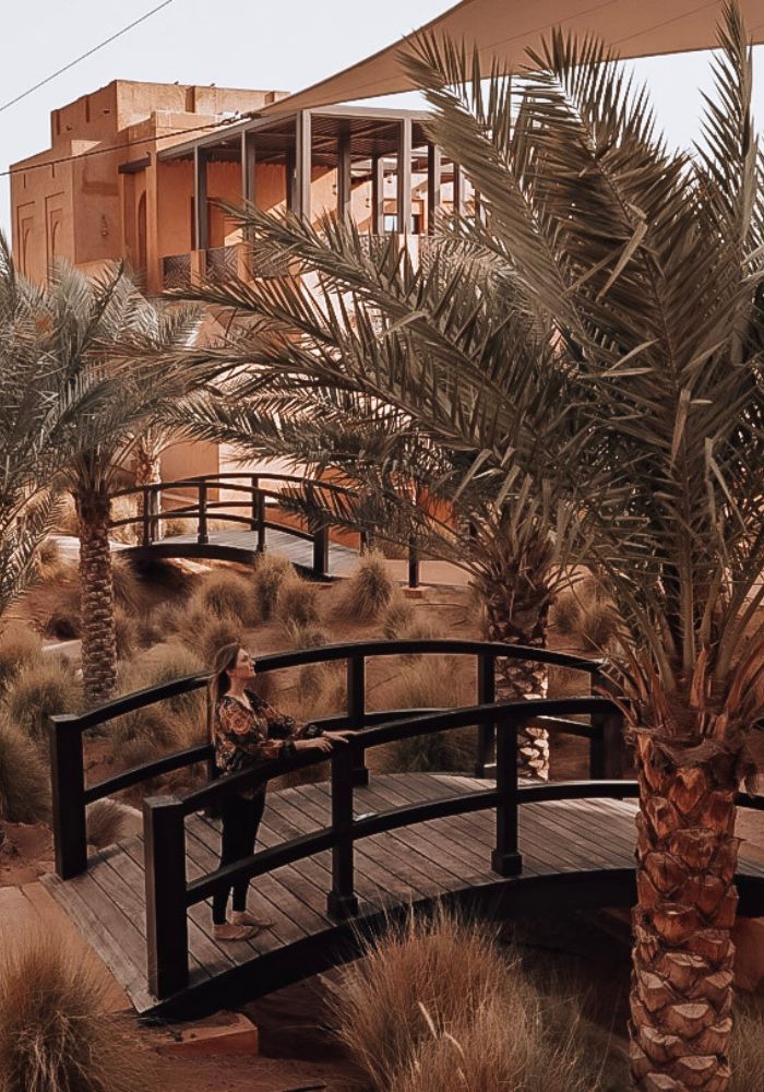 Monica on a bridge under a palm tree - Is It Safe to Travel to Dubai as a Solo Female?