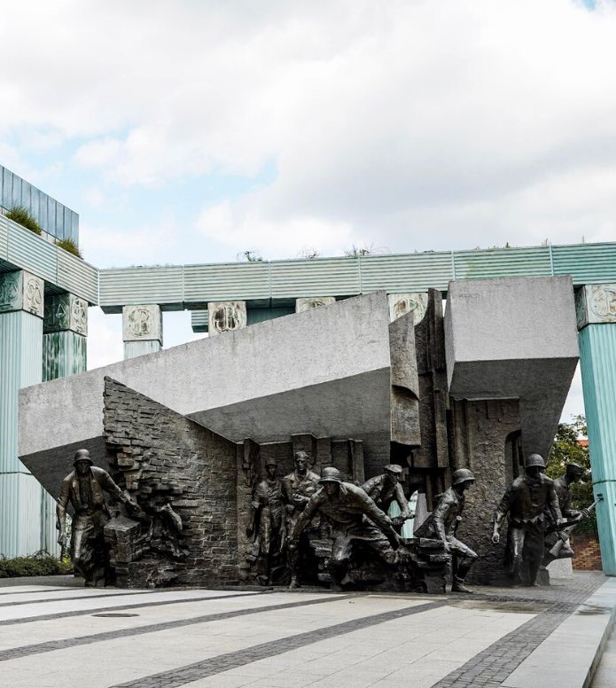 The Uprising Monument, featuring soldiers in front of sculptural bricks and blue pillars - one of the best thigns to do in Warsaw.