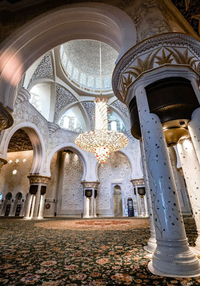 The interior of the Sheik Zayed Grand Mosque, showing the ornate carpet and chandelier.