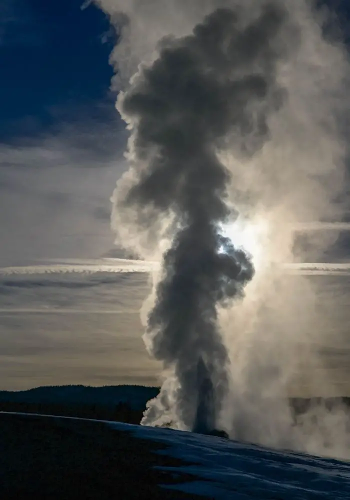 The geyser erupting in front of an early morning moon on A Salt Lake City to Yellowstone National Park Road Trip.