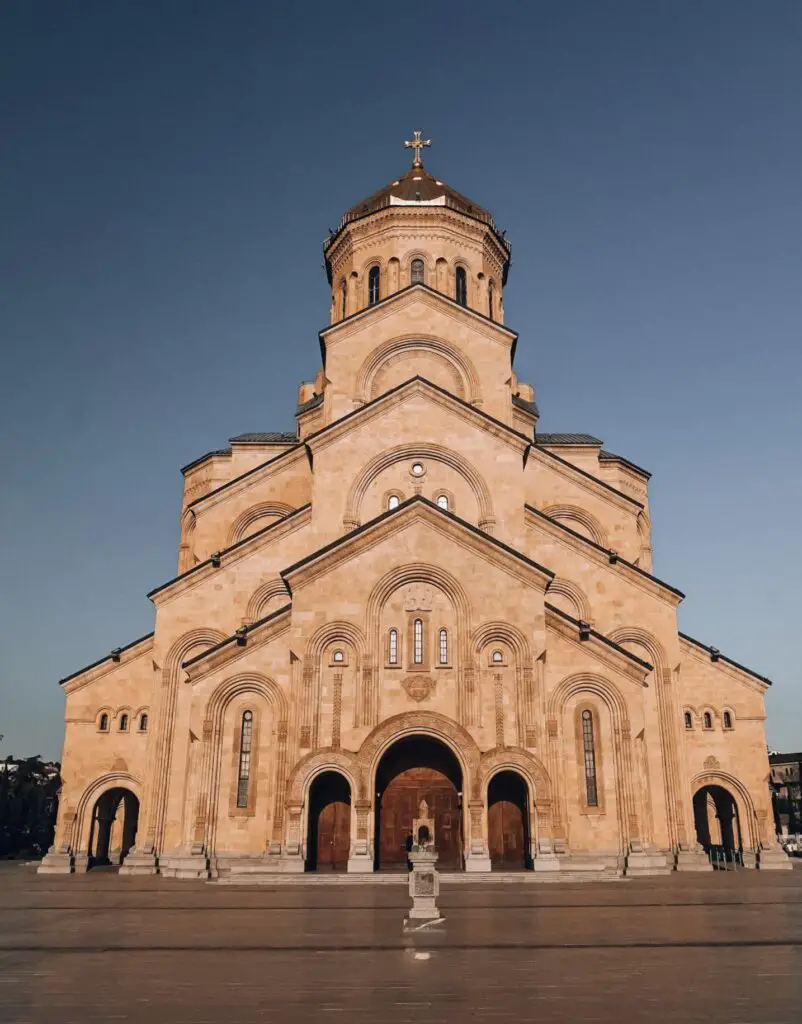 The facade of Sameba Holy Trinity Cathedral in Tbilisi, Georgia, against a blue sky.