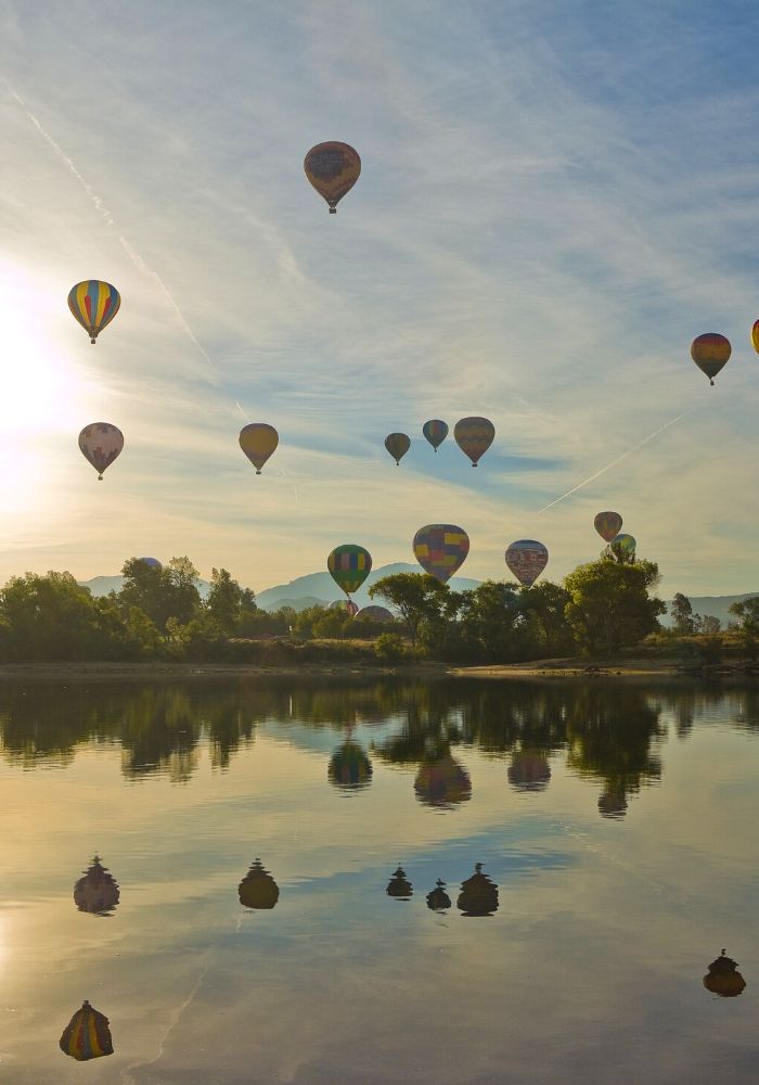 Hot air balloons flying in the sky over a lake in Temecula, a great stop on A San Diego to Joshua Tree Road Trip.