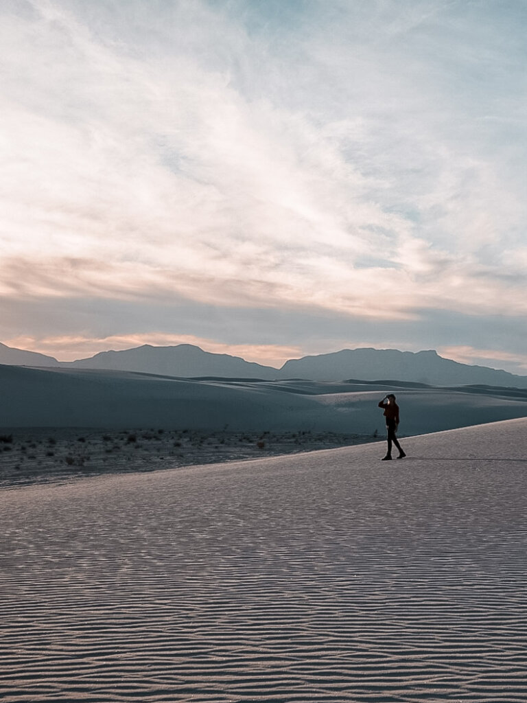 Monica watching a sunset in the desert, one of the best Things to Do in White Sands National Park, New Mexico.