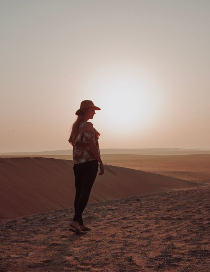 Monica in the pink hued sunrise in the Arabian Desert.