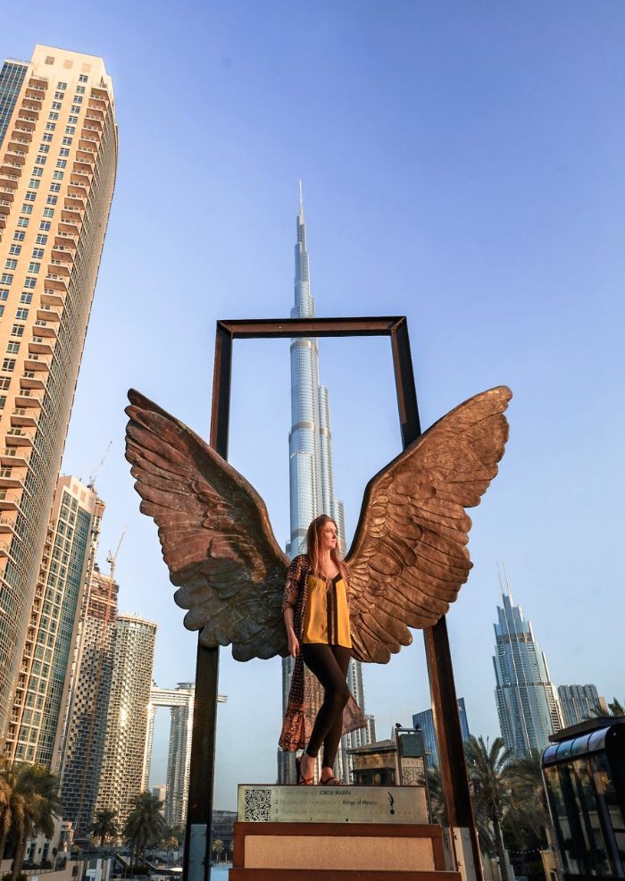 Monica in a yellow shirt at the Wings of Mexico sculpture in Dubai.