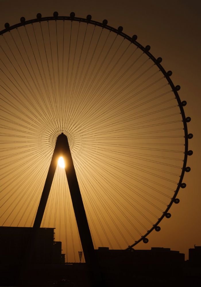 The world's tallest ferris wheel at sunset, in front of an orange sky.