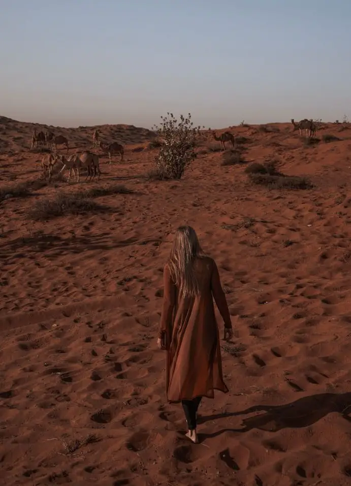Monica in the desert wearing conservative clothing, being mindful of what NOT to do in Dubai as far as dress.