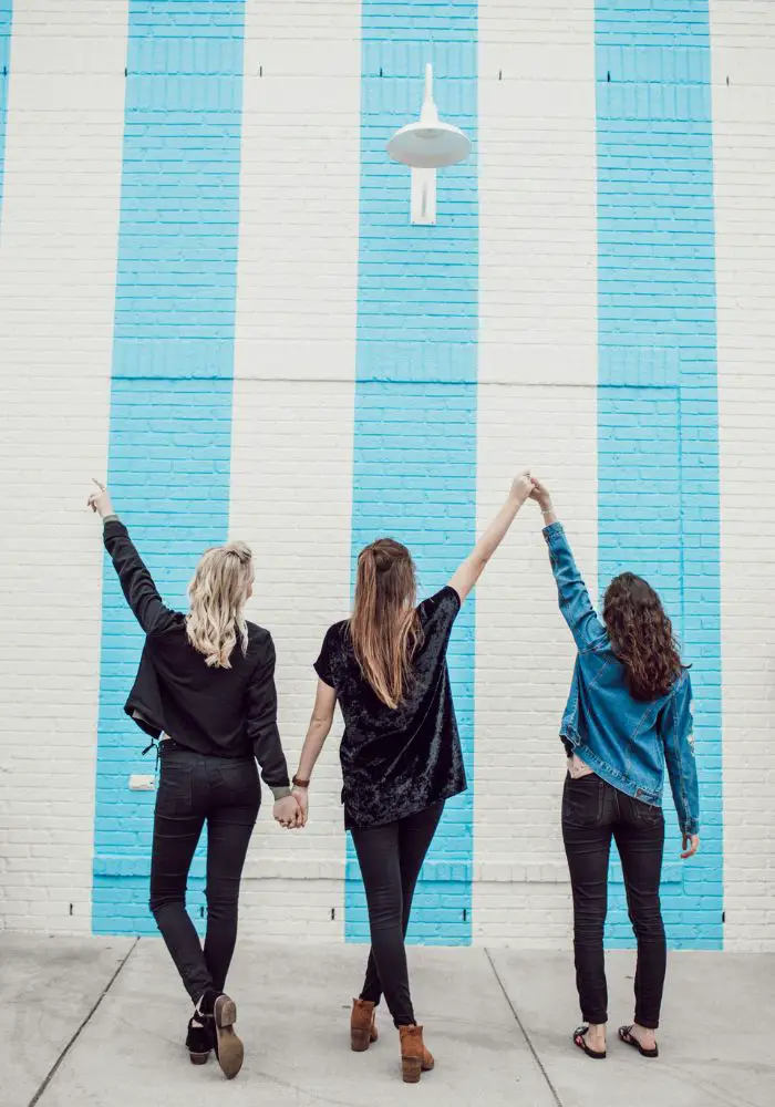 Things to Do on a Road Trip with Friends - three friends taking a photo near a colorful wall.