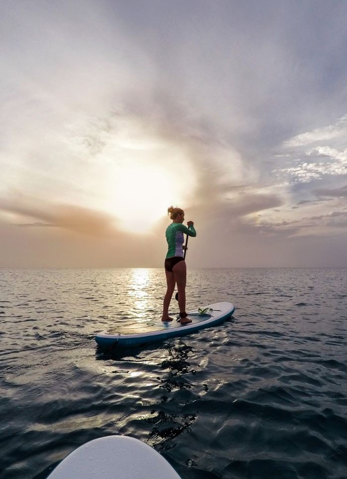 Girl on a paddleboard in Tahiti - A Moorea & Tahiti Packing List for the beach.