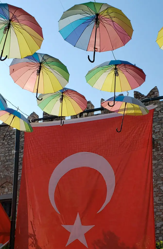 The red Turkish flag under colorful unmrellas - a One Day in Istanbul Itinerary.