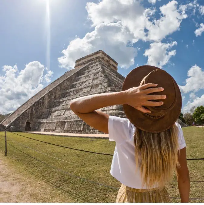 Girl in a brown hat looking out to the Mayan ruins in Cancun.