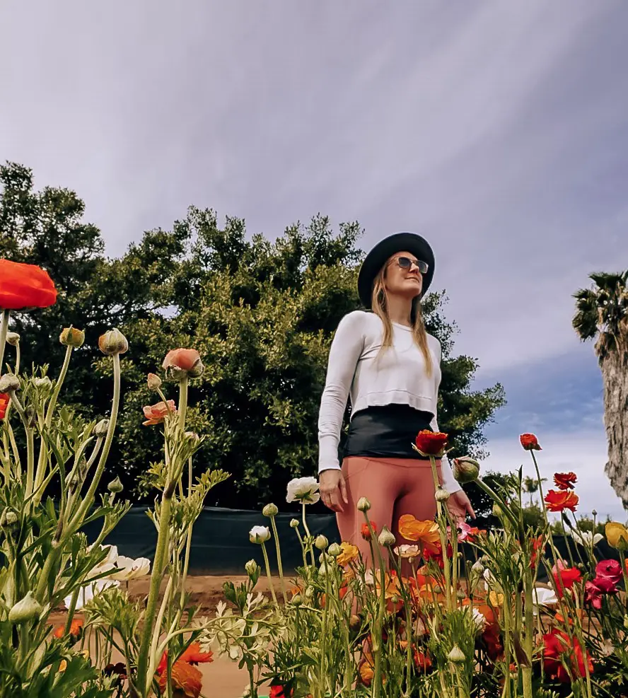 Monica standing near a row of bright and colorful flowers at The Carlsbad Flower Fields.