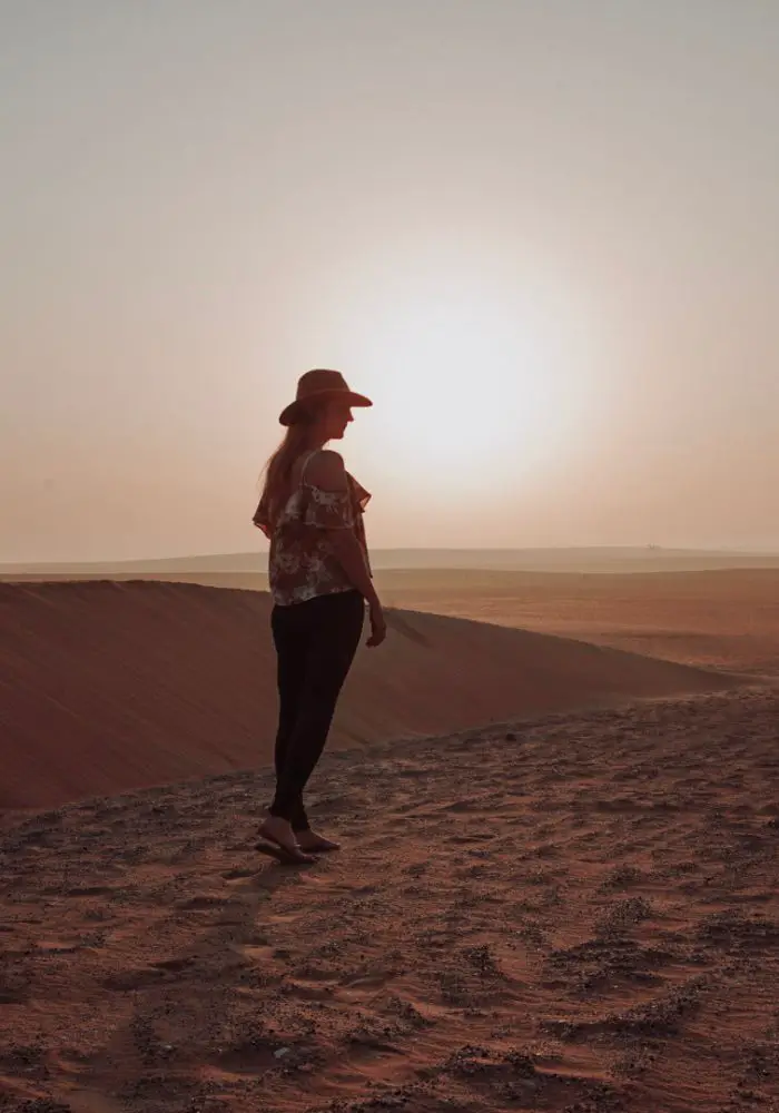 Monica in the Arabian Desert at sunrise - Doha vs. Dubai: Which is Better?