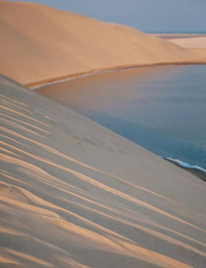 Qatar's desert dunes against the sea - Doha vs. Dubai: Which is Better?