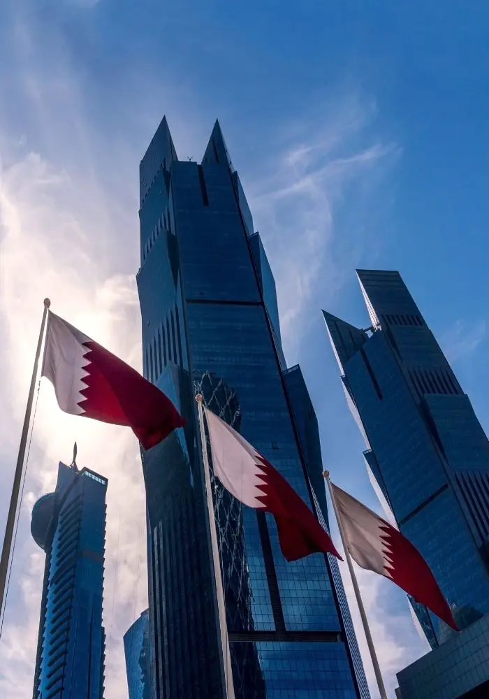 Qatar flags in front of tall skyscrapers - Doha vs. Dubai: Which is Better?