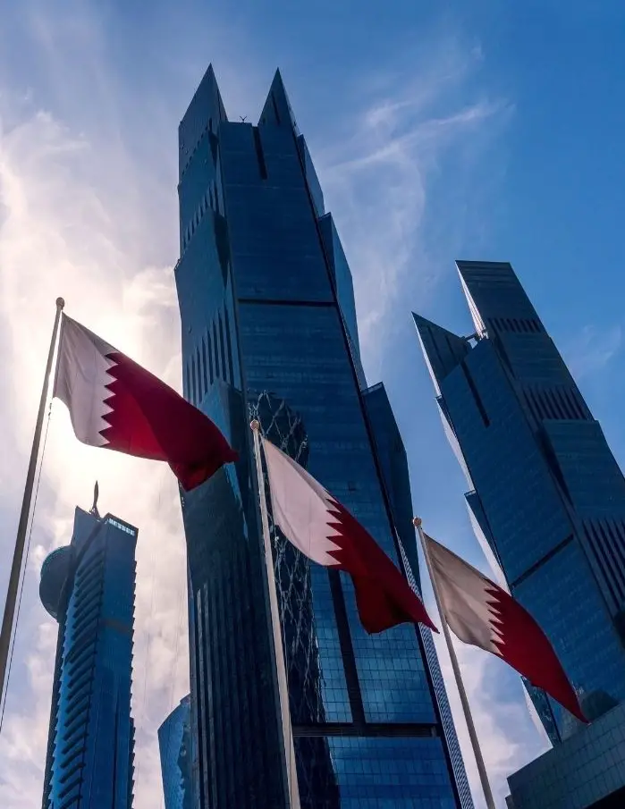Qatar flags in front of Doha skyscrapers.