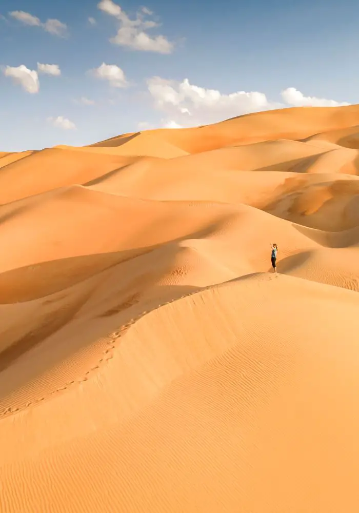 Far away girl on the endless dunes of A Liwa Desert Safari.